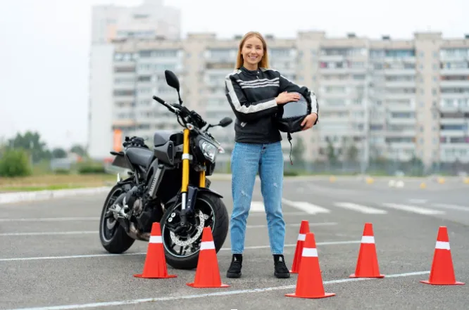 jeune femme sur un parcours de permis a2 à côté de sa moto d’occasion avec un casque à la main